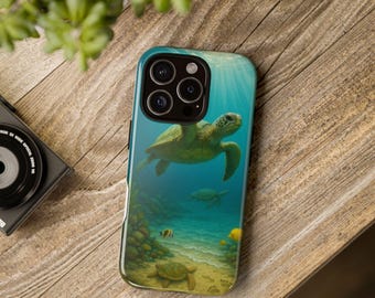 May include: A phone case featuring a vibrant underwater scene with a green sea turtle swimming in blue water. The design includes coral, fish, and a sandy seabed. The case is on a wooden surface.