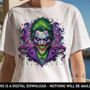 May include: A white t-shirt featuring a colourful graphic of the Joker from Batman. The Joker is depicted with green hair, purple and green clothing, and a menacing grin. The graphic is surrounded by colourful paint splatters.