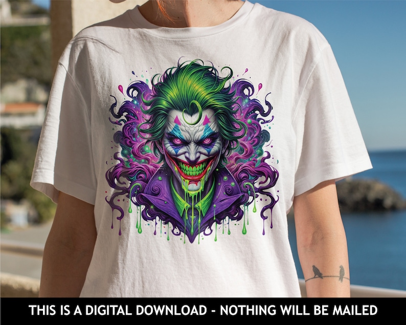 May include: A white t-shirt featuring a colourful graphic of the Joker from Batman. The Joker is depicted with green hair, purple and green clothing, and a menacing grin. The graphic is surrounded by colourful paint splatters.