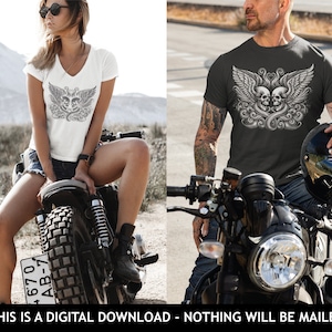 Op de afbeelding: Een wit T-shirt met een afbeelding van twee schedels met vleugels. De schedels zijn grijs en de vleugels zijn zwart. Het T-shirt wordt gedragen door iemand die op een motorfiets zit.