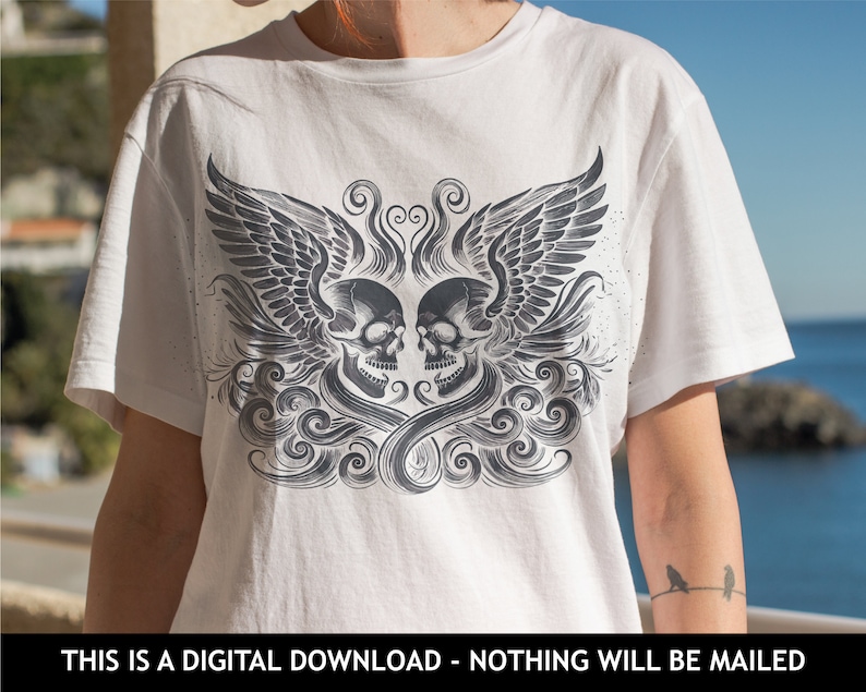 Op de afbeelding: Wit T-shirt met een zwart-wit grafisch ontwerp van twee schedels met vleugels en een wervelend patroon.