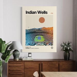 May include: A retro-style poster with a minimalist design featuring a tennis stadium with a crowd of people. The poster has the text "Indian Wells /CA" and "Founded/2000" and "Coordinates/33.7238"N, 116.3059"W".