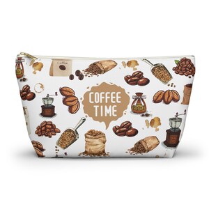 May include: White zippered pouch with a coffee theme. The pouch is decorated with a repeating pattern of coffee beans, coffee bags, coffee grinders, and scoops. The text "COFFEE TIME" is written in a brown speech bubble.