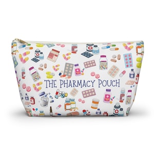 May include: White zippered pouch with a colorful pattern of pills, bottles, and pill packs. The text "THE PHARMACY POUCH" is printed in blue on the pouch.
