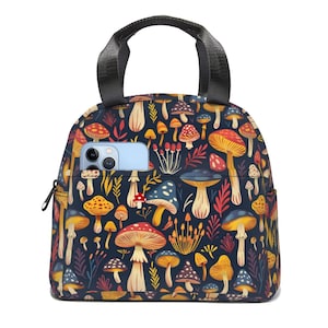 Op de afbeelding: Een zwarte lunchtas met een ritssluiting en een handvat. De tas is bedekt met een kleurrijk patroon van paddenstoelen en bladeren.