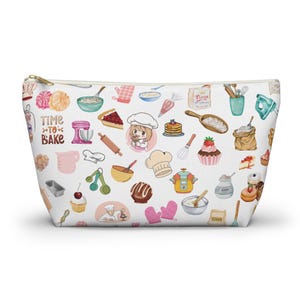 May include: White zippered pouch with a colorful pattern of baking-themed illustrations. The pattern includes a cartoon chef, cupcakes, cherries, a rolling pin, a whisk, a bowl of flour, and the text "Time to Bake".