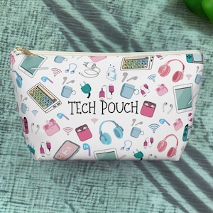 May include: White zippered pouch with a repeating pattern of tech accessories, including headphones, charging cables, and smart devices. The pouch has the text "TECH POUCH" printed on the front.