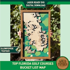 May include: Wooden framed map of Florida golf courses. The map is laser-cut with a light wood finish, featuring black and white markers indicating golf course locations. The background is green with golf course illustrations. Text on the map reads "Golf Florida" and "Top Florida Golf Courses Bucket List Map."
