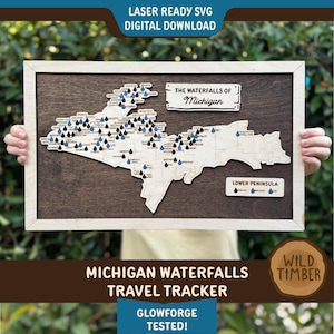 May include: Wooden framed map of Michigan with laser-cut waterfalls marked with blue and black teardrop pins. The text "THE WATERFALLS OF Michigan" is displayed above the map. The text "MICHIGAN WATERFALLS TRAVEL TRACKER" is displayed below the map.