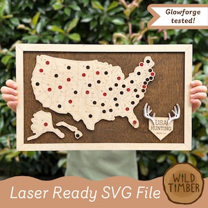 Può includere: Una mappa da parete rettangolare in legno degli Stati Uniti con contorni degli stati tagliati al laser, ritagli circolari e una targa a forma di scudo con corna di cervo e il testo USA HUNTING - Bucket List su una base scura.
