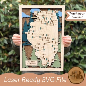 May include: Wooden map of Illinois State Parks with laser-cut details. The map features a light wood frame, a detailed map of Illinois, and small tree icons marking park locations. Text includes "Illinois State Parks" and "Track your travels!"