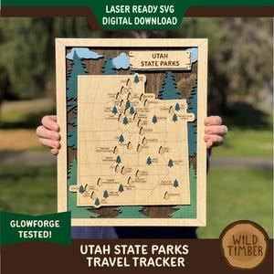 May include: A laser-cut wooden map of Utah State Parks, featuring a green and brown color scheme. The map is labeled "Utah State Parks Travel Tracker" and includes the names of various parks.