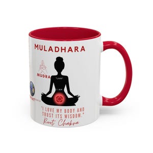 May include: White ceramic mug with a red interior and handle. The mug features the word "MULADHARA" in red, a silhouette of a person in a yoga pose, and the text "I LOVE MY BODY AND TRUST ITS WISDOM." Root Chakra.