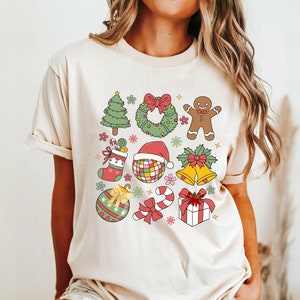 A retro Christmas Coquette graphic on a Comfort Colors shirt. The graphic has colors of red, green, gold and pink with a 3x3 pattern of Christmas elements. The shirt comes in 14 pretty colors.