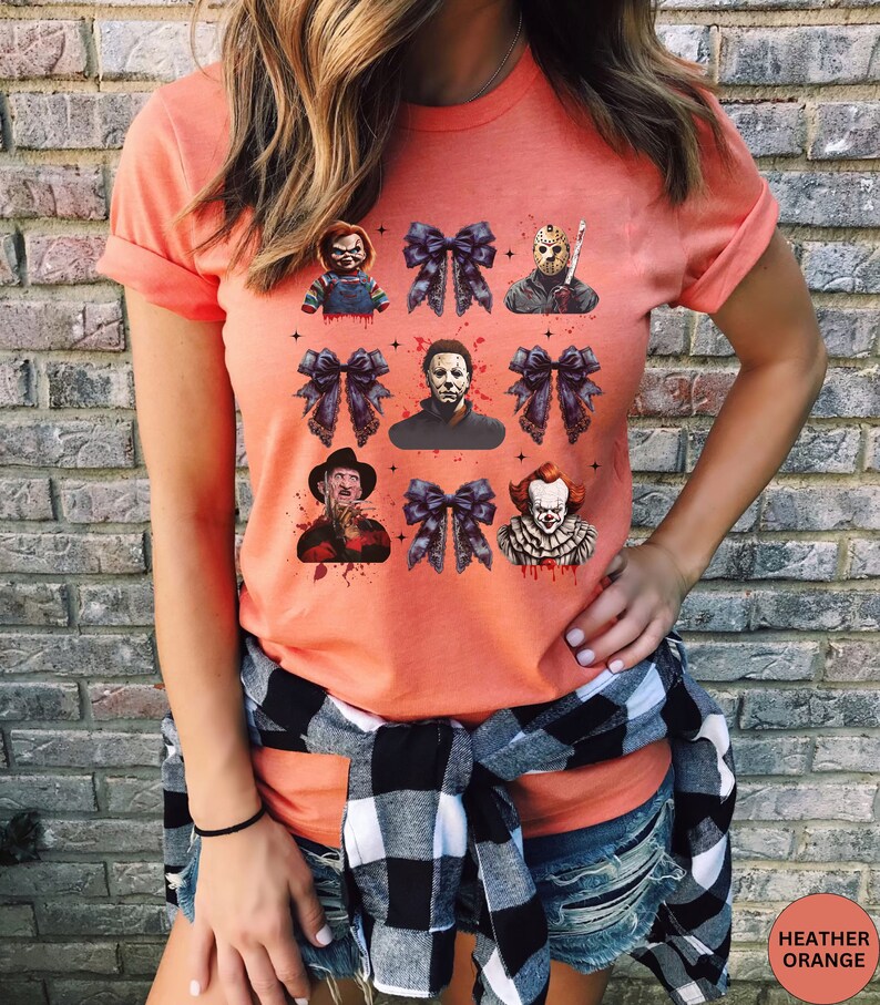 May include: A heather orange t-shirt with a graphic print of horror movie characters with black bows. The characters include Freddy Krueger, Jason Voorhees, Pennywise, Michael Myers, and Chucky.