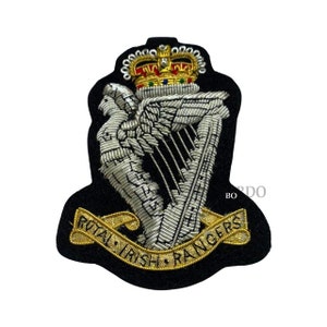 May include: Embroidered patch with a harp, crown, and the words "Royal Irish Rangers" in gold thread on black fabric. The harp and crown are intricately detailed with silver and gold thread.