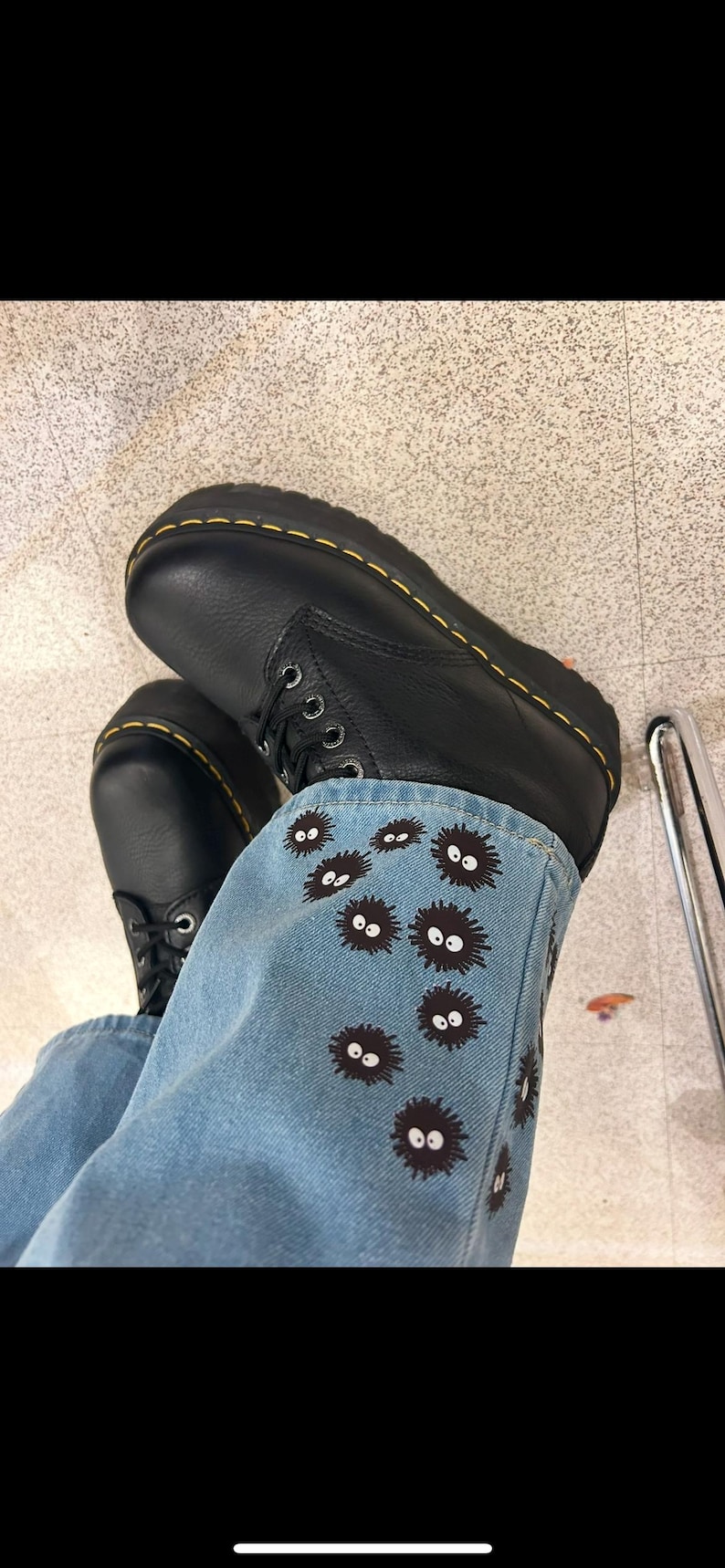 May include: Black leather boots with yellow stitching and a pair of blue jeans with black and white embroidered characters.
