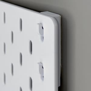 Peut inclure: Un panneau perfor&eacute; rectangulaire blanc dot&eacute; d'une grille de fentes ovales verticales r&eacute;guli&egrave;rement espac&eacute;es. Le panneau est fix&eacute; avec un bloc d'espacement blanc &eacute;pais dans le coin, cr&eacute;ant un petit espace entre la plaque et le mur.