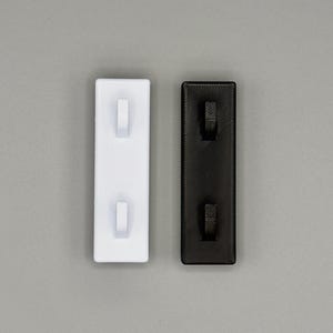 Peut inclure: Deux organisateurs muraux rectangulaires, l'un en blanc uni et l'autre en noir uni. Chaque organisateur comporte deux petits crochets saillants align&eacute;s verticalement sur une plaque de base plate et textur&eacute;e, con&ccedil;us pour suspendre des objets.