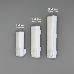 Peut inclure: Trois crochets muraux adh&eacute;sifs blancs de tailles diff&eacute;rentes. Le plus petit est marqu&eacute; 4 LB Max Standard, le moyen 10 LB Max Heavy Duty et le plus grand 15 LB Max Super Duty. Chaque crochet pr&eacute;sente une base rectangulaire blanche avec une bande adh&eacute;sive.