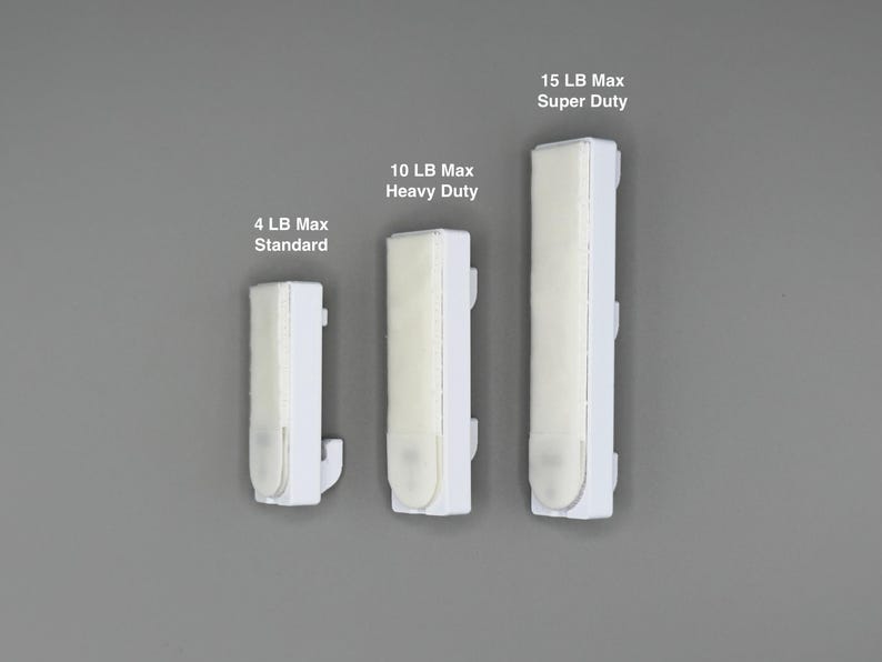 Peut inclure: Trois crochets muraux adh&eacute;sifs blancs de tailles diff&eacute;rentes. Le plus petit est marqu&eacute; 4 LB Max Standard, le moyen 10 LB Max Heavy Duty et le plus grand 15 LB Max Super Duty. Chaque crochet pr&eacute;sente une base rectangulaire blanche avec une bande adh&eacute;sive.