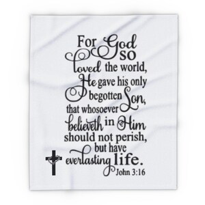 May include: White throw blanket with black text that reads "For God so loved the world, He gave his only begotten Son, that whosoever believeth in Him should not perish, but have everlasting life. John 3:16". A black cross with a wreath is in the bottom left corner.