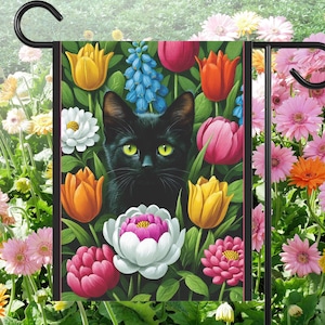 May include: A garden flag featuring a black cat with yellow eyes surrounded by colorful flowers. The flowers include yellow, orange, pink, and white tulips, and blue grape hyacinths. The flag is designed for outdoor use.