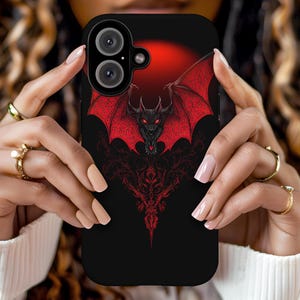May include: A black phone case with a red and black dragon design. The dragon has a red body and wings with black accents. The phone case has a camera lens cutout.