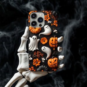 May include: A black iPhone case with a Halloween theme. The case features a pattern of orange pumpkins, white ghosts, and black and white flowers.