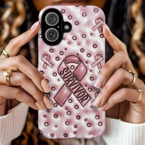 May include: A pink and white phone case with a pink ribbon and the word "SURVIVOR" in a white circle. The case is decorated with small white dots.