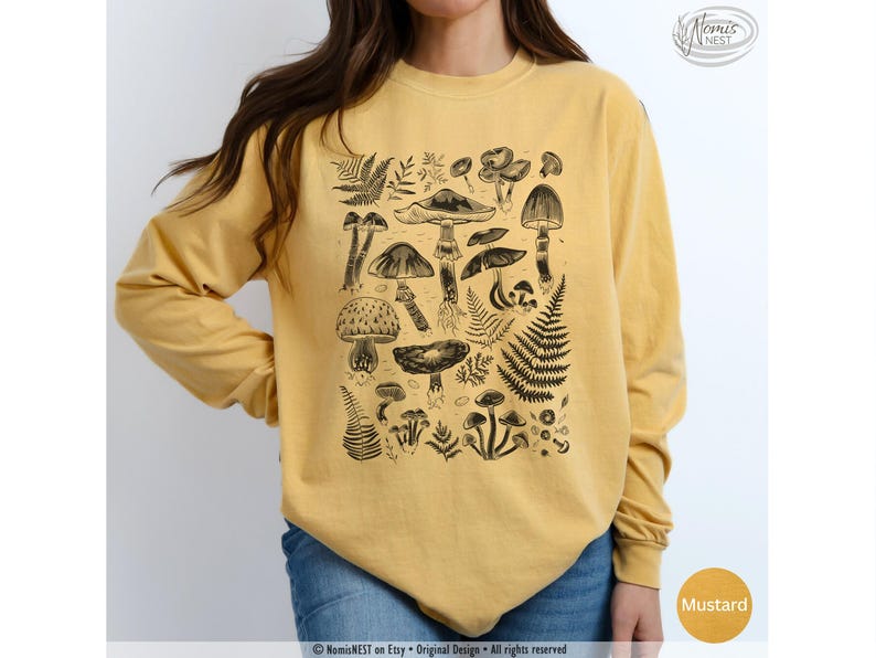 A mustard colored Comfort Colors long sleeve mushroom graphic t-shirt featuring illustrated botanical mushrooms which is perfect for granola girls, mushroom fans, those seeking a forestcore aesthetic, or nature lovers.