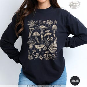 A black colored Comfort Colors long sleeve mushroom graphic t-shirt featuring illustrated botanical mushrooms which is perfect for granola girls, mushroom fans, those seeking a forestcore aesthetic, or nature lovers.