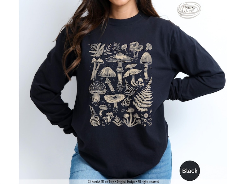 A black colored Comfort Colors long sleeve mushroom graphic t-shirt featuring illustrated botanical mushrooms which is perfect for granola girls, mushroom fans, those seeking a forestcore aesthetic, or nature lovers.