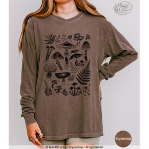 An espresso colored Comfort Colors long sleeve mushroom graphic t-shirt featuring illustrated botanical mushrooms which is perfect for granola girls, mushroom fans, those seeking a forestcore aesthetic, or nature lovers.