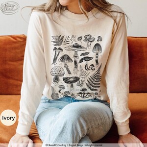 An ivory colored Comfort Colors long sleeve mushroom graphic t-shirt featuring illustrated botanical mushrooms which is perfect for granola girls, mushroom fans, those seeking a forestcore aesthetic, or nature lovers.