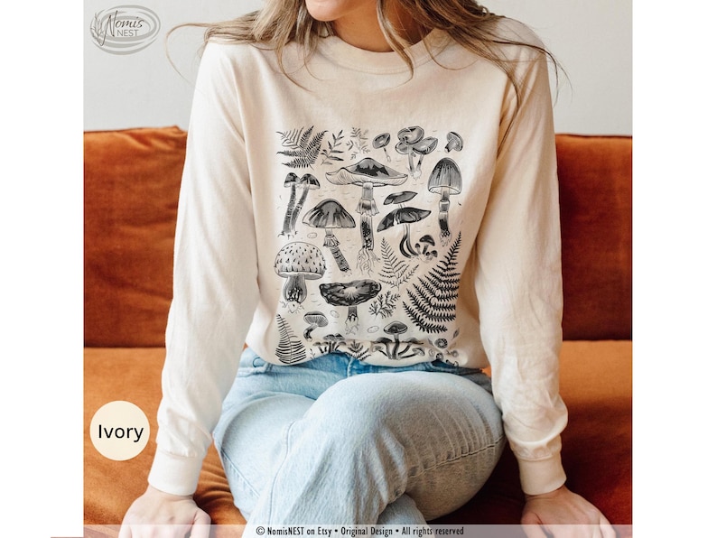 An ivory colored Comfort Colors long sleeve mushroom graphic t-shirt featuring illustrated botanical mushrooms which is perfect for granola girls, mushroom fans, those seeking a forestcore aesthetic, or nature lovers.