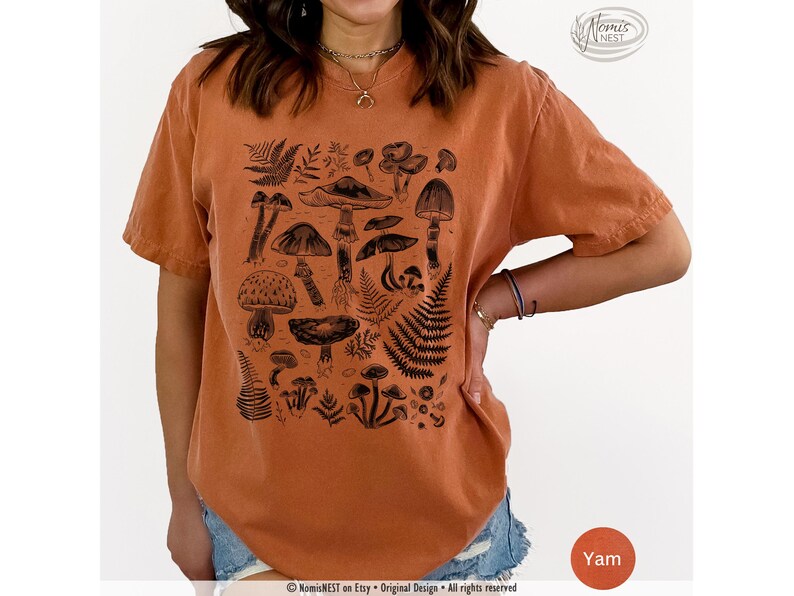A yam colored Comfort Colors graphic t-shirt featuring a monochromatic array of illustrated botanical mushrooms. It’s a perfect gift for nature lovers, mushroom foragers, granola girls, and forest wanderers.