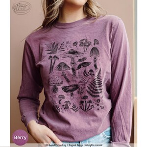 A berry colored Comfort Colors long sleeve mushroom graphic t-shirt featuring illustrated botanical mushrooms which is perfect for granola girls, mushroom fans, those seeking a forestcore aesthetic, or nature lovers.