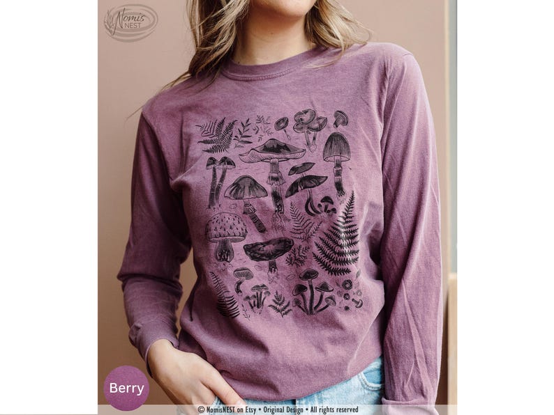 A berry colored Comfort Colors long sleeve mushroom graphic t-shirt featuring illustrated botanical mushrooms which is perfect for granola girls, mushroom fans, those seeking a forestcore aesthetic, or nature lovers.