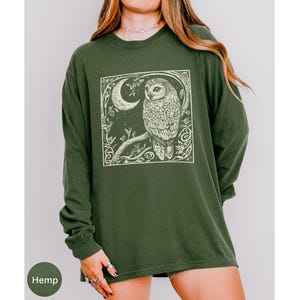 A long sleeve Comfort Colors graphic t-shirt with a linocut style Snowy Owl evoking a witchy, magical, & Dark Academia vibe.