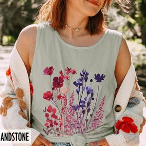 A model is wearing a Comfort Colors tank top with pressed wildflowers in a mix of reds, berries, and pastel colors.