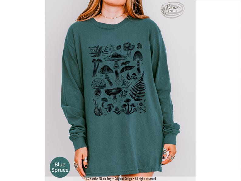 A blue spruce colored Comfort Colors long sleeve mushroom graphic t-shirt featuring illustrated botanical mushrooms which is perfect for granola girls, mushroom fans, those seeking a forestcore aesthetic, or nature lovers.