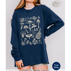 A true navy colored Comfort Colors long sleeve mushroom graphic t-shirt featuring illustrated botanical mushrooms which is perfect for granola girls, mushroom fans, those seeking a forestcore aesthetic, or nature lovers.