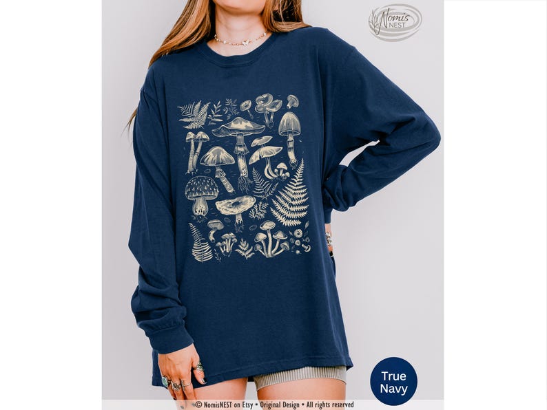 A true navy colored Comfort Colors long sleeve mushroom graphic t-shirt featuring illustrated botanical mushrooms which is perfect for granola girls, mushroom fans, those seeking a forestcore aesthetic, or nature lovers.