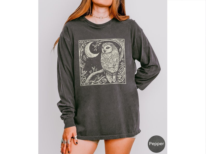 A long sleeve Comfort Colors graphic t-shirt with a linocut style Snowy Owl evoking a witchy, magical, & Dark Academia vibe.