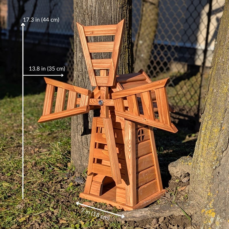 May include: A wooden windmill garden ornament with a natural brown finish. It features four slatted blades and a central tower structure. Dimensions are 44 cm in height, 35 cm in blade width, and 18 cm in base width as indicated in the image.