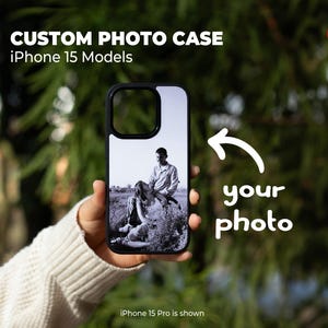 May include: Black iPhone 15 model phone case with a custom photo. The case features a black border and a black and white photo of a couple. Text on the case reads "CUSTOM PHOTO CASE iPhone 15 Models" and "your photo."