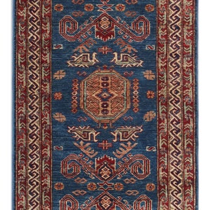 May include: A blue and red patterned rug with a geometric design. The rug has a fringe border.