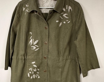 May include: A green button-up shirt with white embroidered floral designs. The shirt has a collared neckline and long sleeves. The brand name "CHICOS" is visible on the label.
