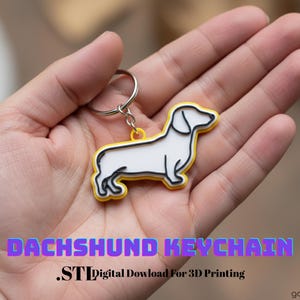 Peut inclure: Un porte-clés teckel avec un corps blanc, des détails noirs et un contour jaune. Le porte-clés est attaché à un anneau argenté. Le texte "DACHSHUND KEYCHAIN" est affiché en violet et bleu.